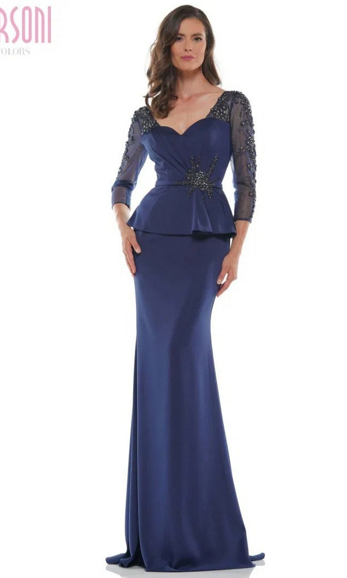A woman in the Marsoni MV1037 long formal dress: a navy floor-length embellished trumpet gown with sheer beaded sleeves, peplum waist, and a star-shaped decorative accent on the bodice.